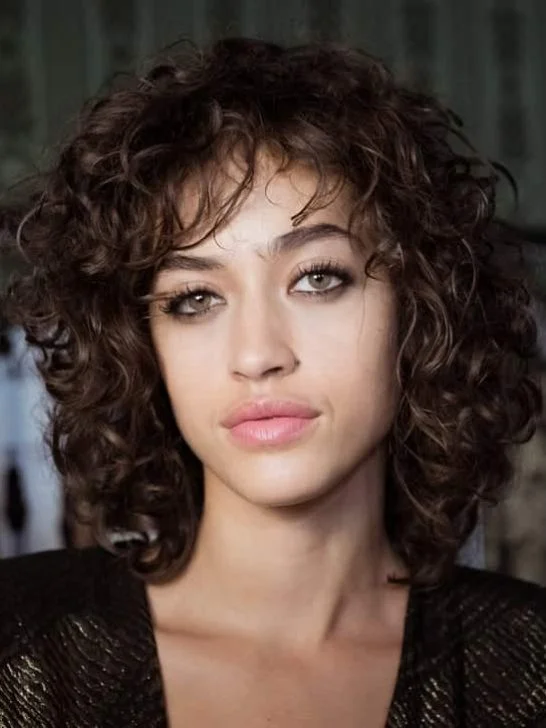 Woman with blunt bangs on curly bob