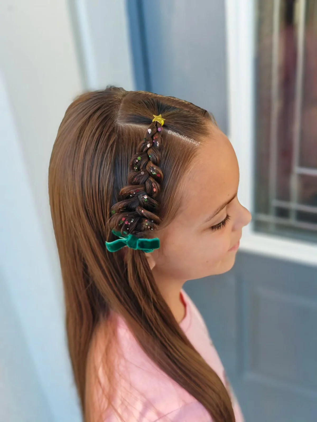 Long brown side braid dusted with glitter and finished with a green bow