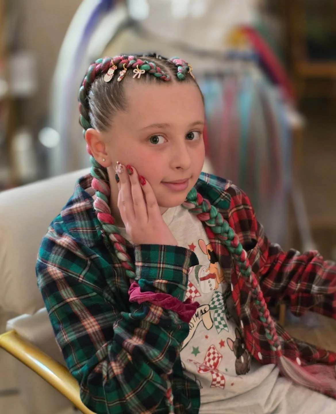 Child with long multicolored braids decorated with small Christmas charms