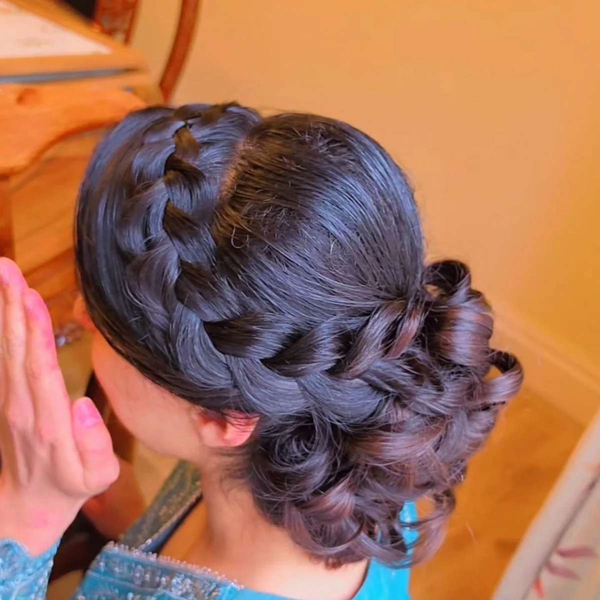 Thick side braid gathered into a voluminous curled bun