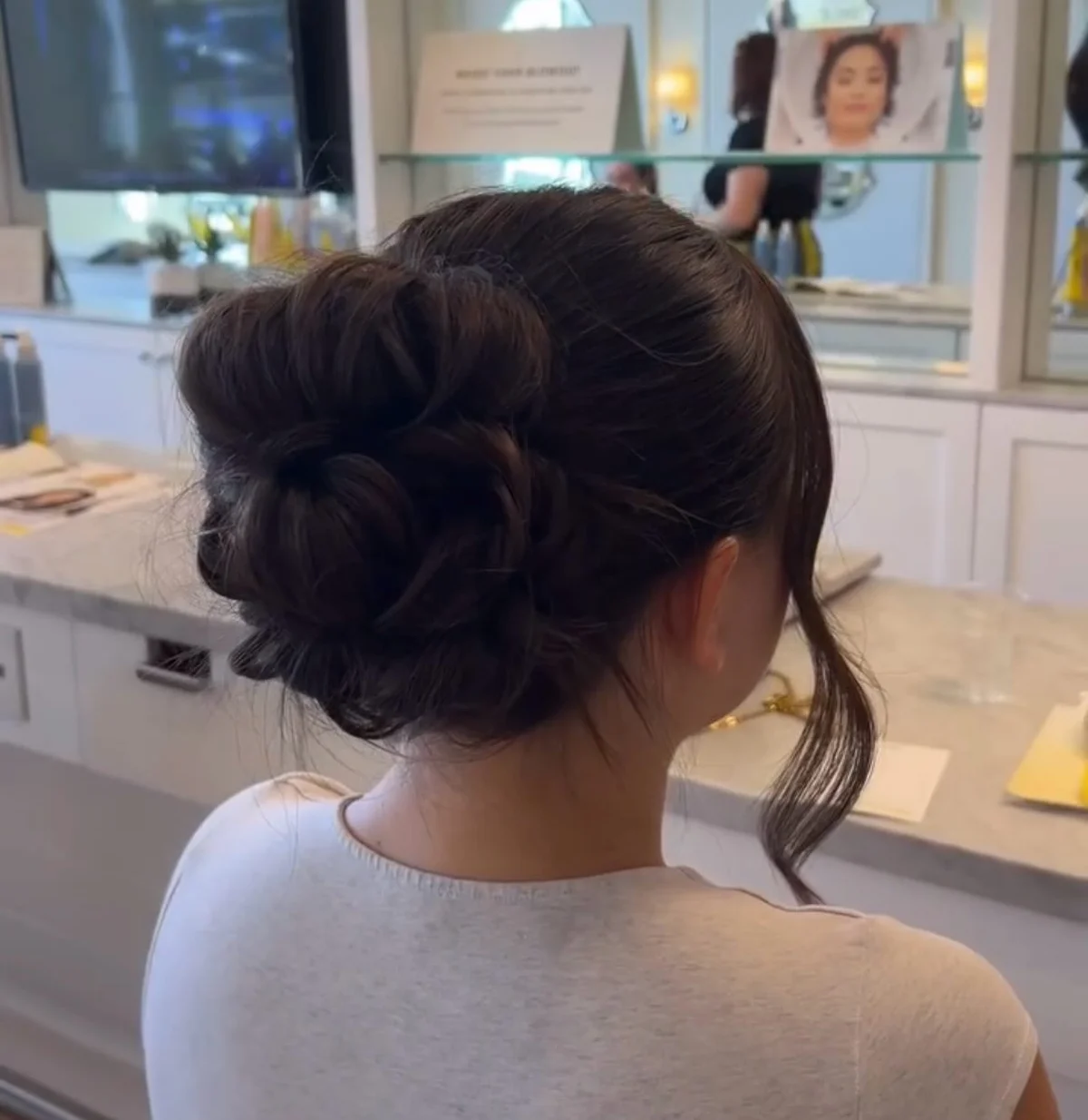 Braided low bun updo in dark brown hair with soft face-framing strands