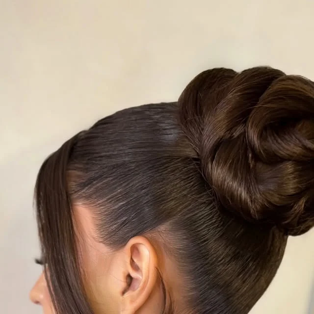 Sleek high bun sculpted with twisted loops of dark brown hair.