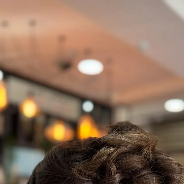 Twisted bun with loose curls framing the nape of the neck.