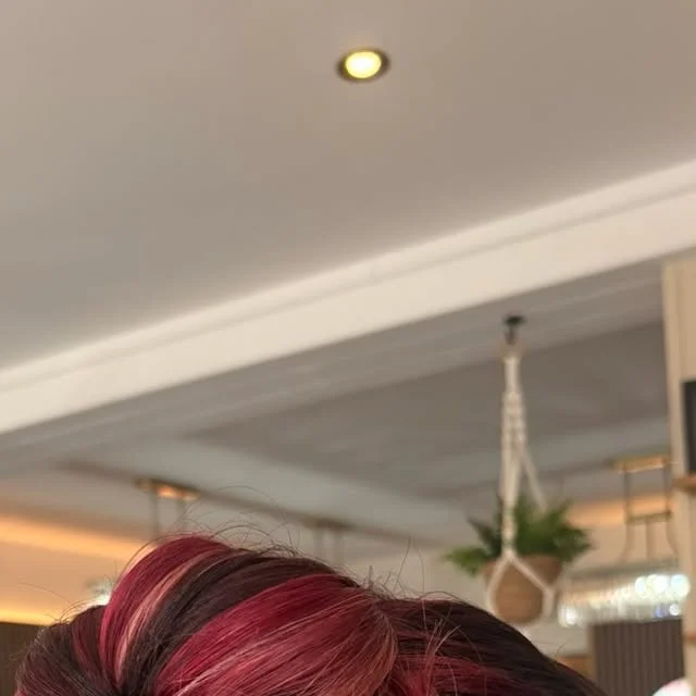 Messy top knot bun with red and pink highlighted strands.