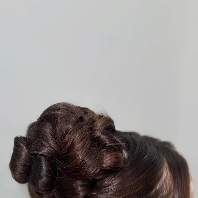 Voluminous twisted bun with curled sections pinned at the back.