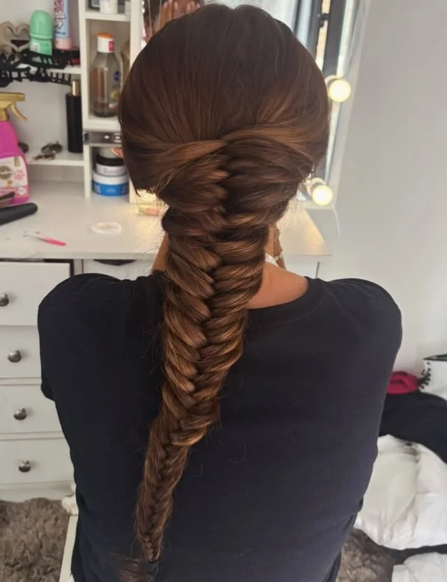 Back view of long brown hair styled into a fishtail braid running down the center of the back.