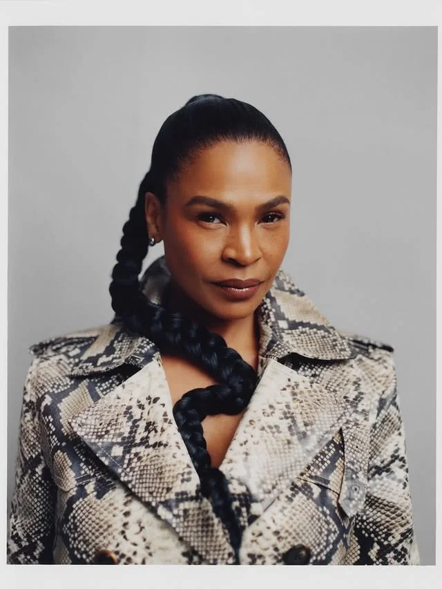Editorial portrait of a woman with sleek black hair pulled into a high ponytail braided into a thick plait.
