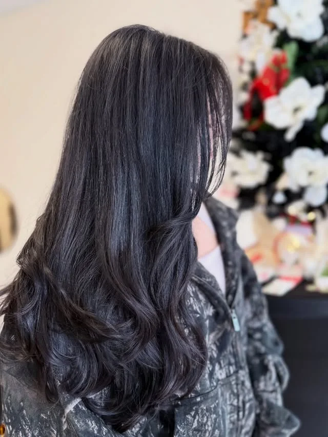 Side and back view of very long black hair worn straight with soft waves and high shine.