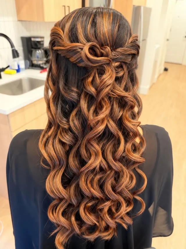 Back view of long dark curly hair with twisted sections pinned into a half-up crown.
