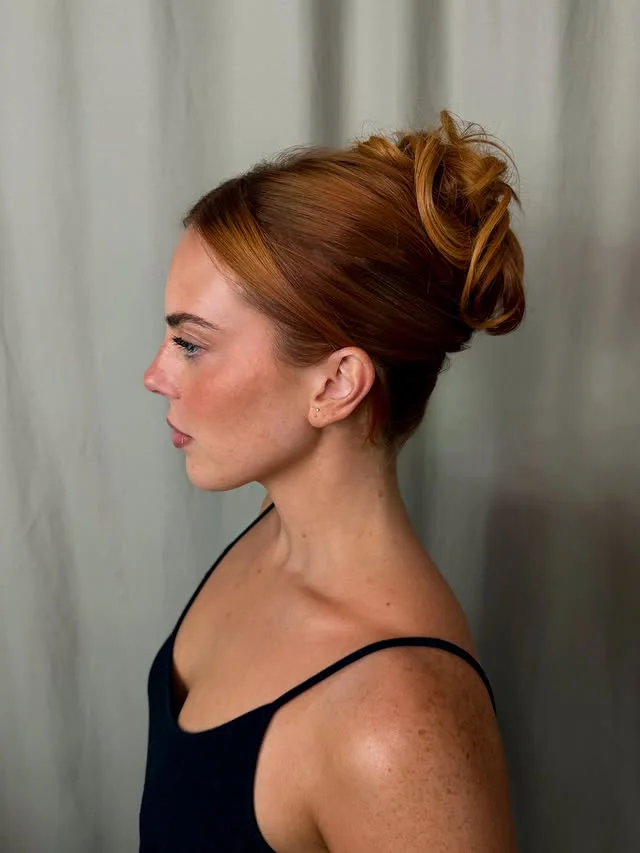Side profile of copper-toned hair swept into a voluminous twisted updo.