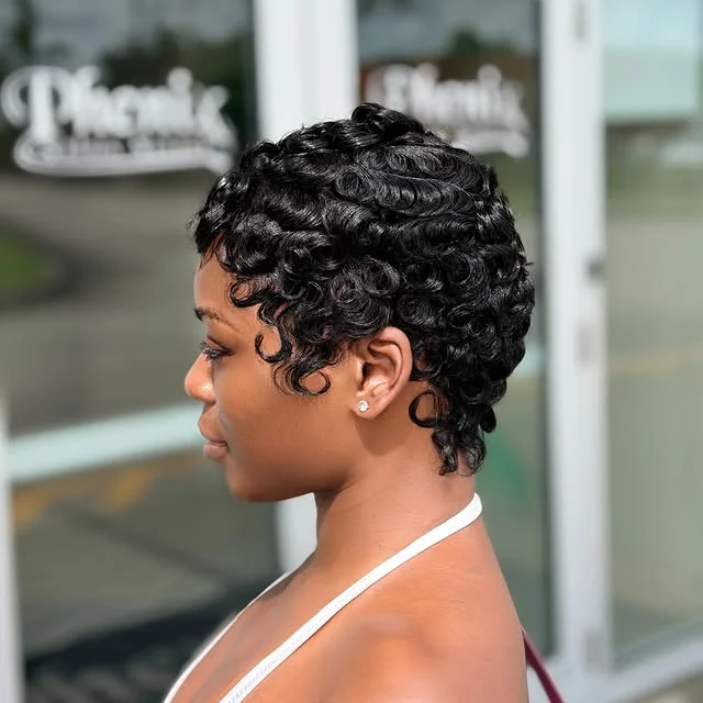 Side view of a woman with a short pixie haircut styled into tight, glossy black curls.