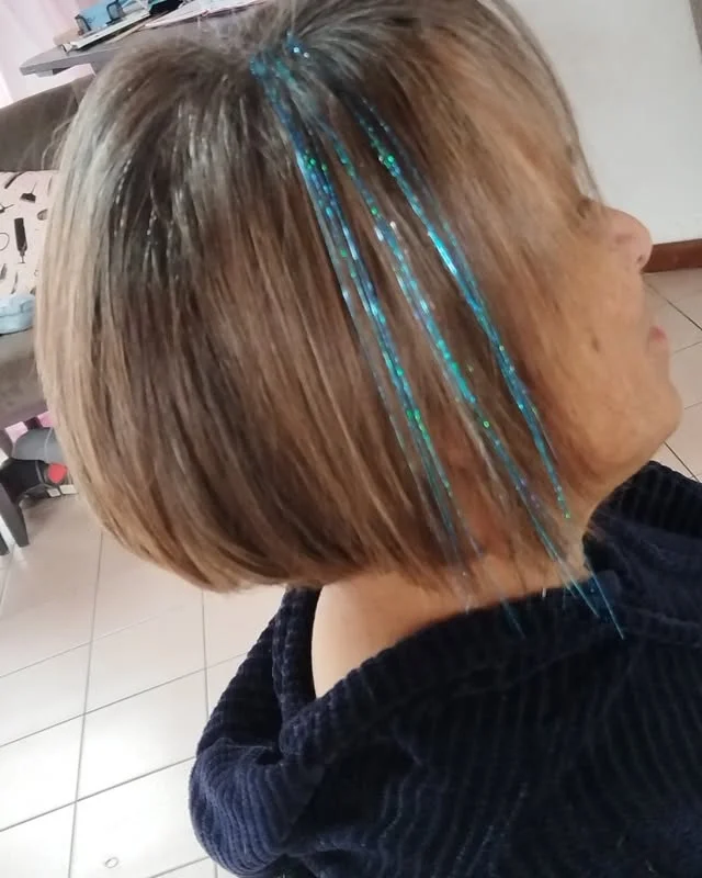 Side view of a chin-length bob with sparkling blue tinsel strands woven into the hair.