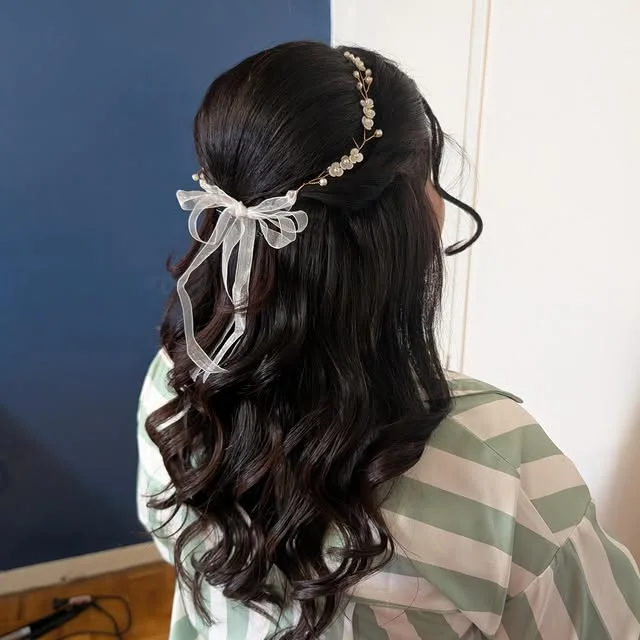Half-updo decorated with a gold pearl hair vine and sheer organza ribbon bow