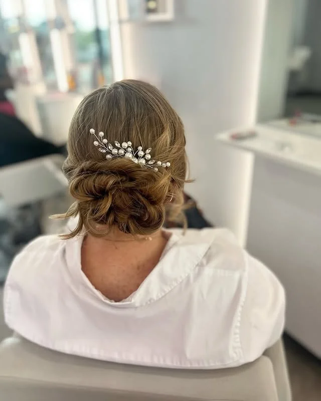Low textured chignon with a delicate pearl and crystal vine hair accessory.
