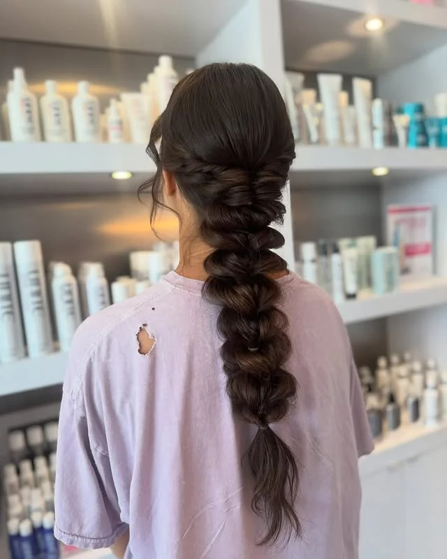 Long boho fishtail braid photographed from behind in a salon.