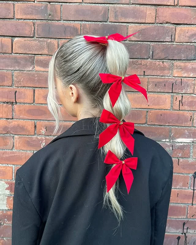 Blonde bubble ponytail decorated with four red velvet bows.