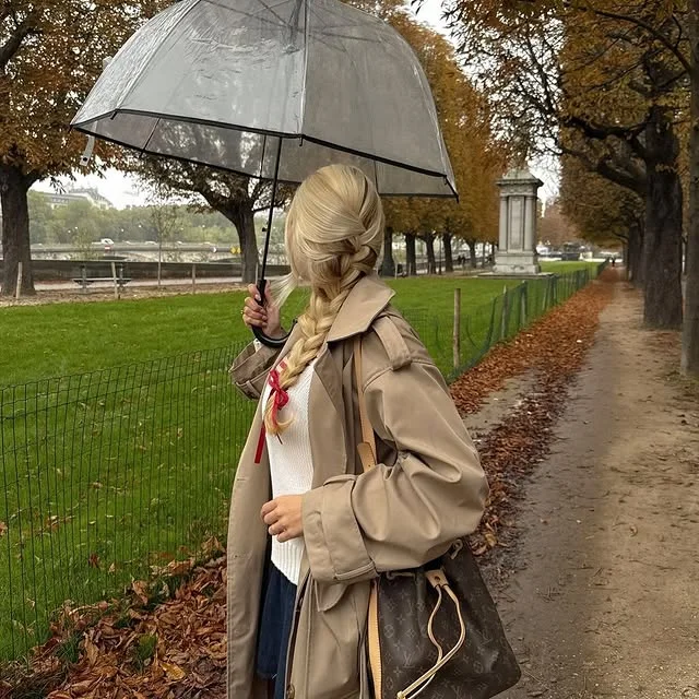 Woman outdoors with a long side braid tied with a red ribbon.