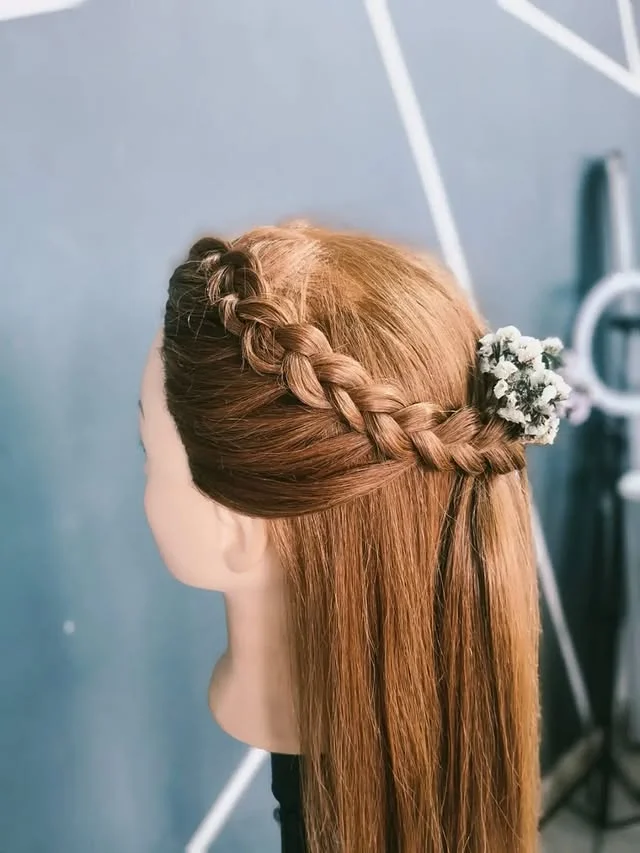 Half-up crown braid with a small floral clip, styled on a mannequin head.