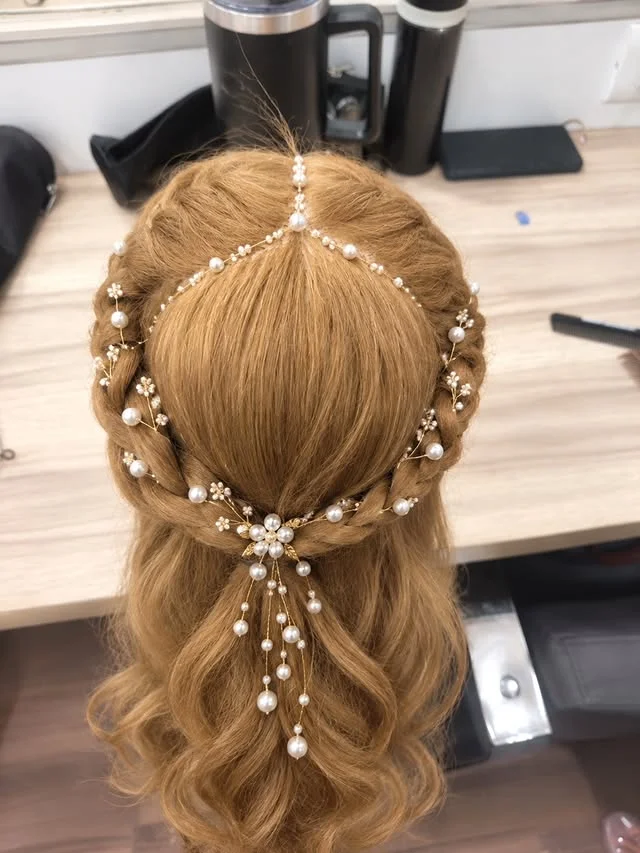 Crown braid on light brown hair decorated with a pearl and gold hair vine.