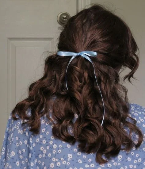 Woman with a ribbon bow tied in curly hair