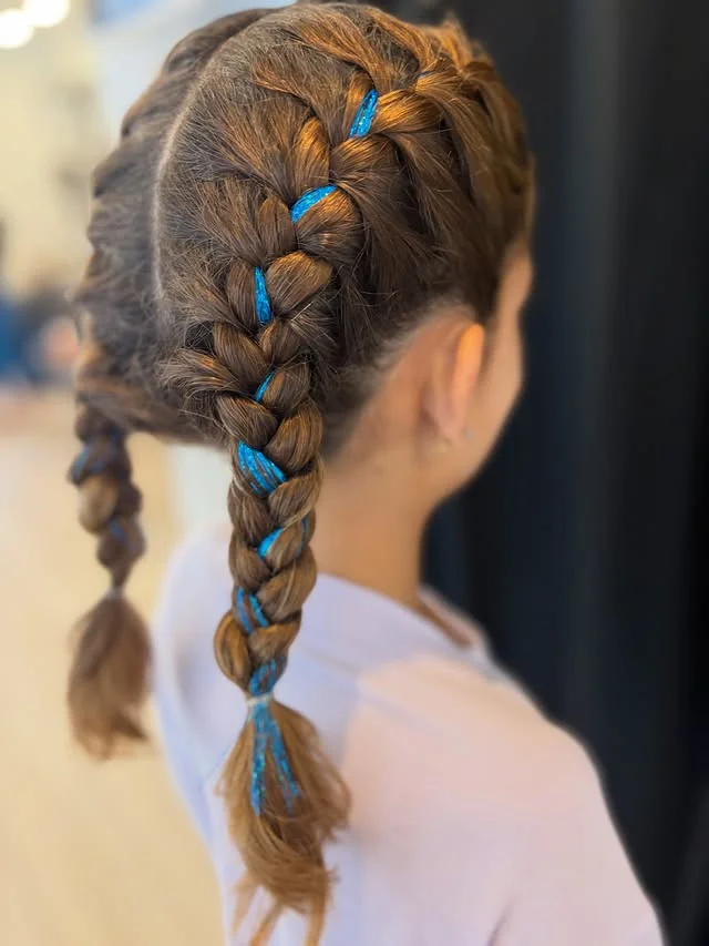 Back view of two brown Dutch braids with bright blue metallic tinsel woven through.