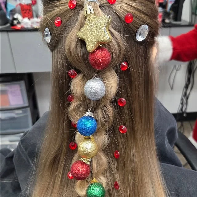 Back view of long hair with a braid decorated with colorful mini Christmas baubles and a glitter star.