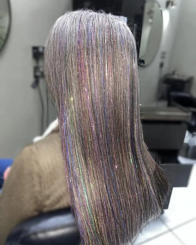 Back view of long straight silver hair with subtle iridescent glitter strands woven through.
