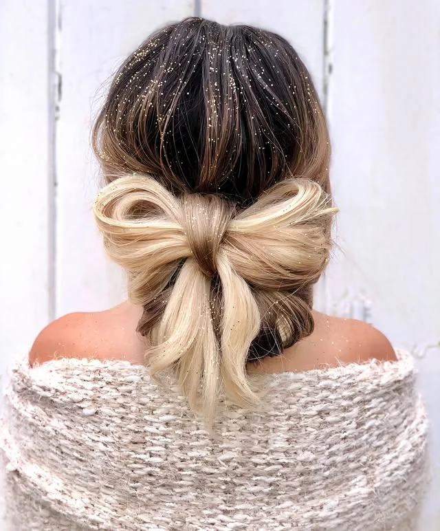 Back view of a large hair bow updo dusted with fine gold glitter.