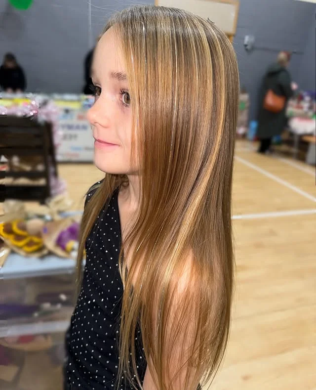 Young girl with long straight hair threaded with fine silver tinsel strands.
