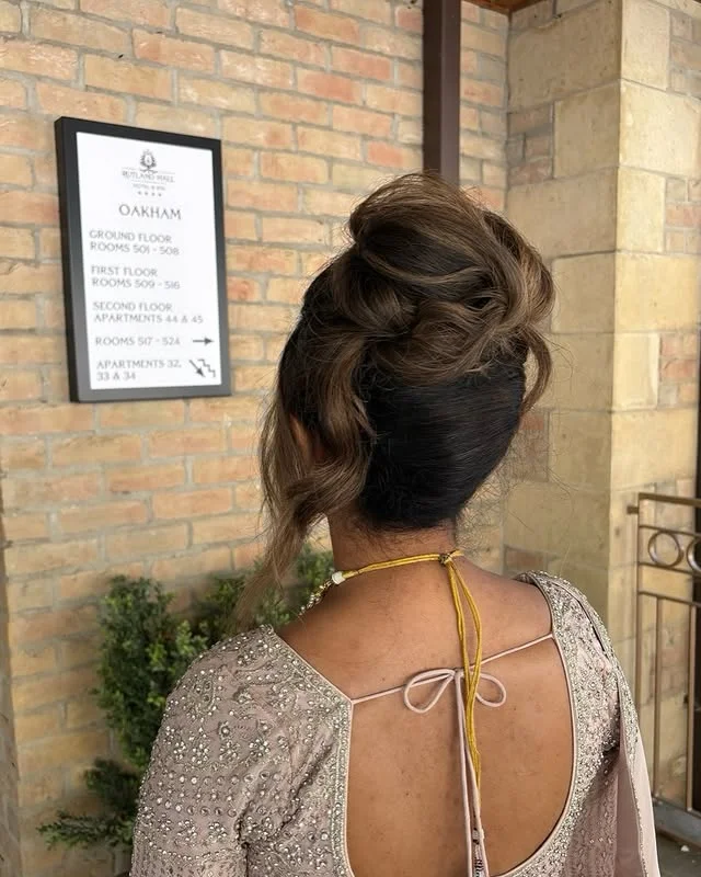 Rear view of a twisted updo with volume and loose tendrils.