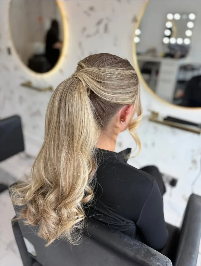 Long wavy blonde hair in a high ponytail with volume at the crown and soft curls at the ends.