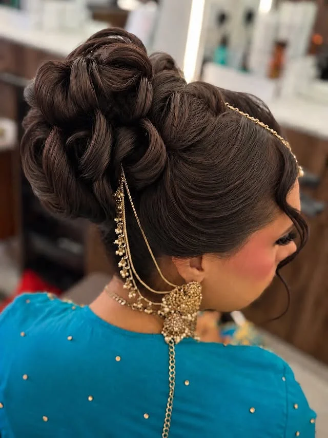 Intricate sculpted updo with smooth interlocking rolls and twists gathered high.