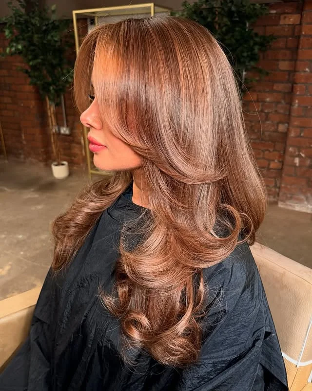 Side profile of a glossy bouncy blow-dry with long layered waves.