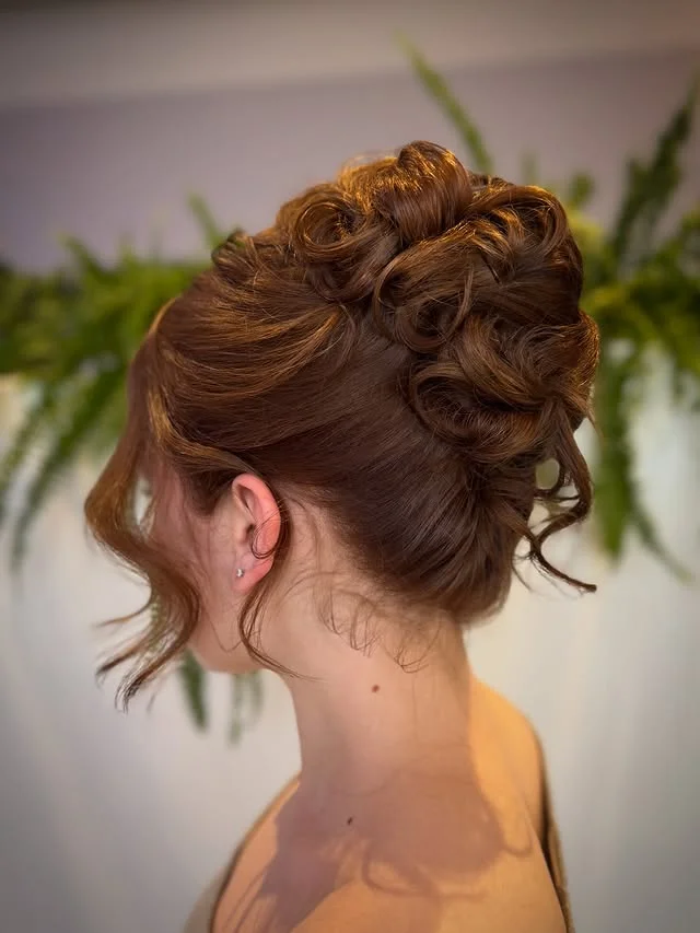 Elaborate brown updo with soft curls pinned at the crown.