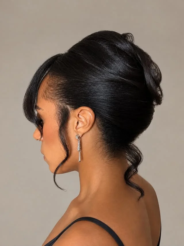 Polished voluminous updo with soft curls framing the nape of the neck.