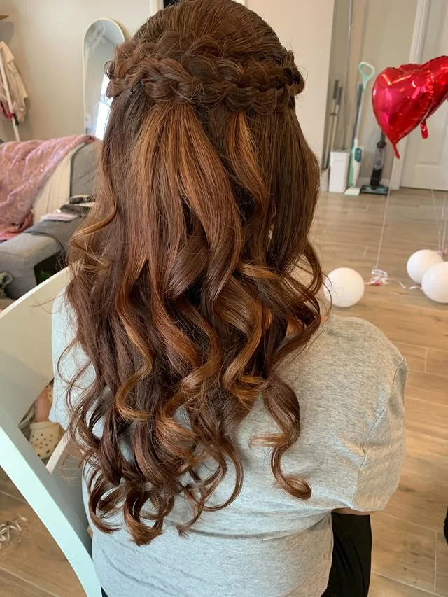 Half-up braid across the crown flowing into voluminous loose curls.