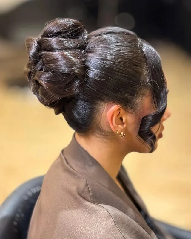 Side profile of a voluminous twisted bun with a sculpted wave framing the face.