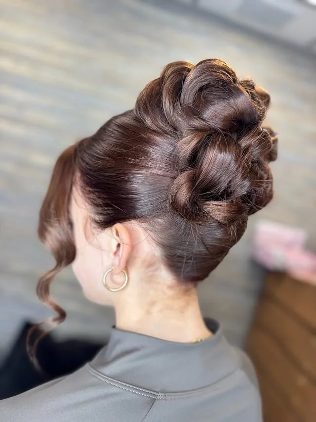 Voluminous twisted updo with sculpted curls piled high at the crown.